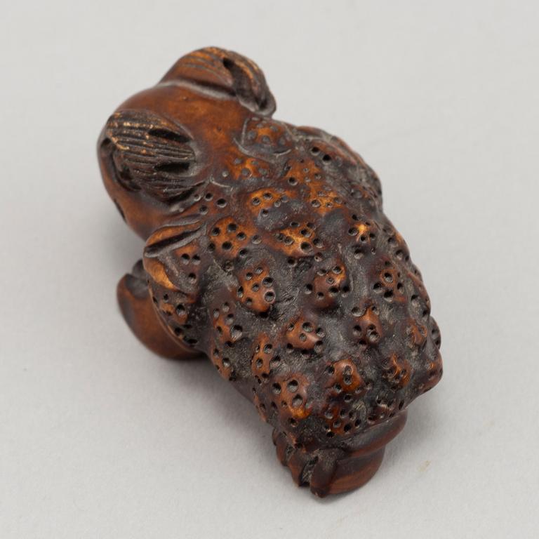 A carved wooden netsuke in the shape of a frog, 20th century.