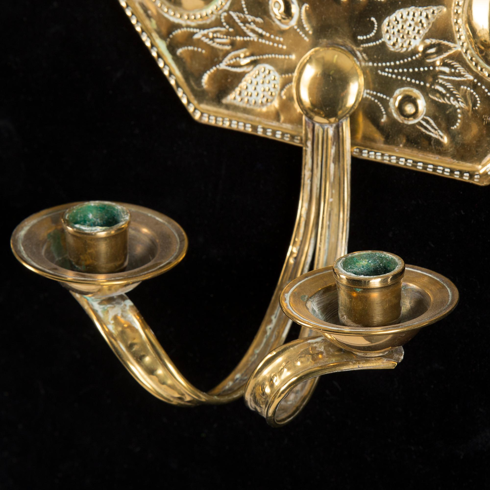 A pair of first half of the 20th century brass two-light wall sconces.