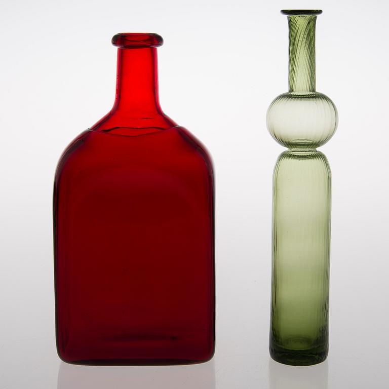 Two glass bottles. A green 'Neptuna' bottle designed by Nanny Still in 1964 and a red bottle from Riihimäen Lasi oy.