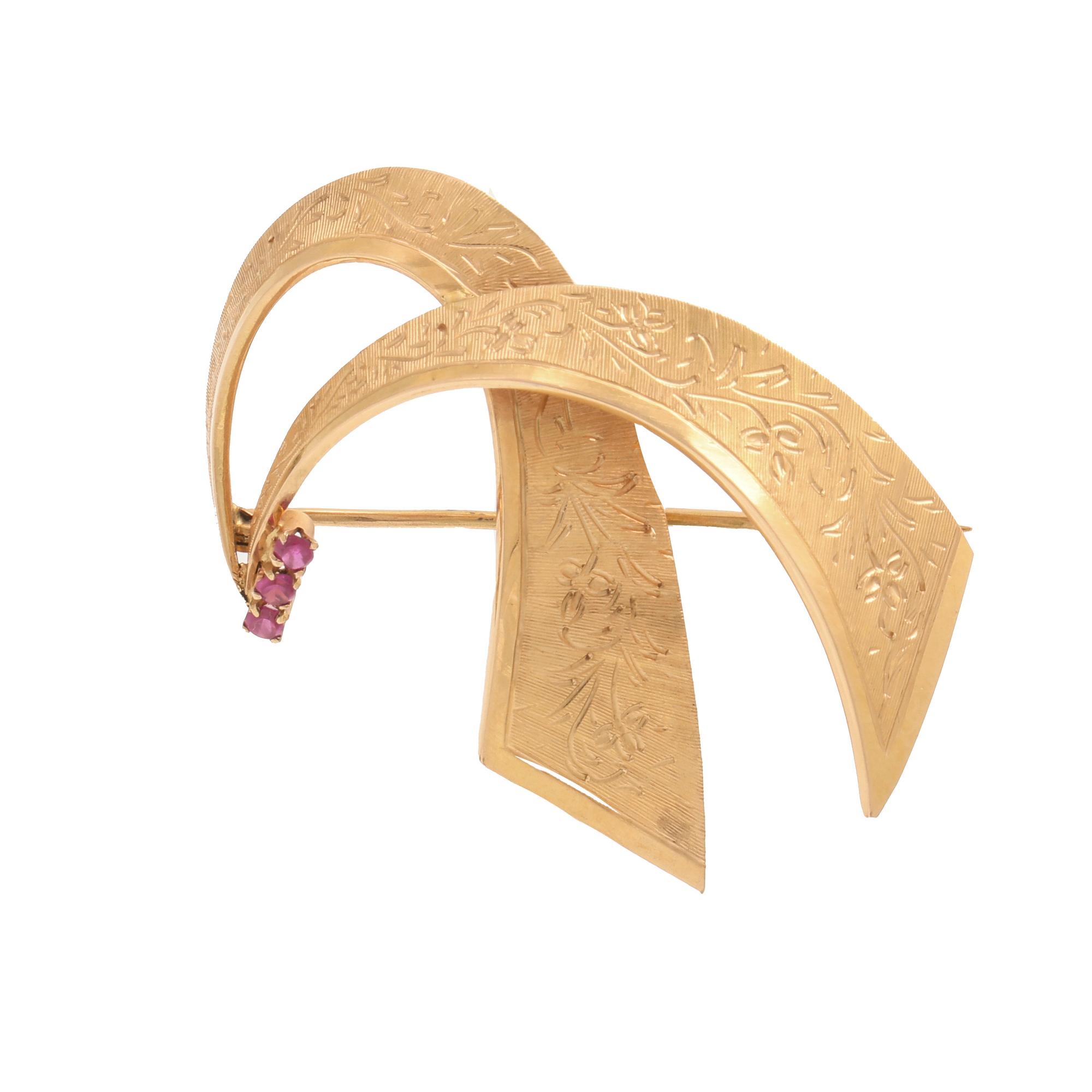 an 18K gold broosch with rubies, possibly synthetic.