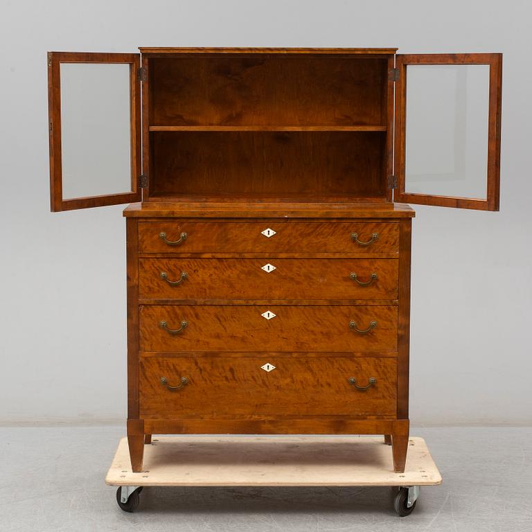 a chest of drawers with a vitrine cabinet from the early 20th century.
