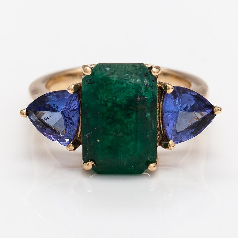 A 14K gold ring with tanzanites and a ca 5.80 ct emerald.