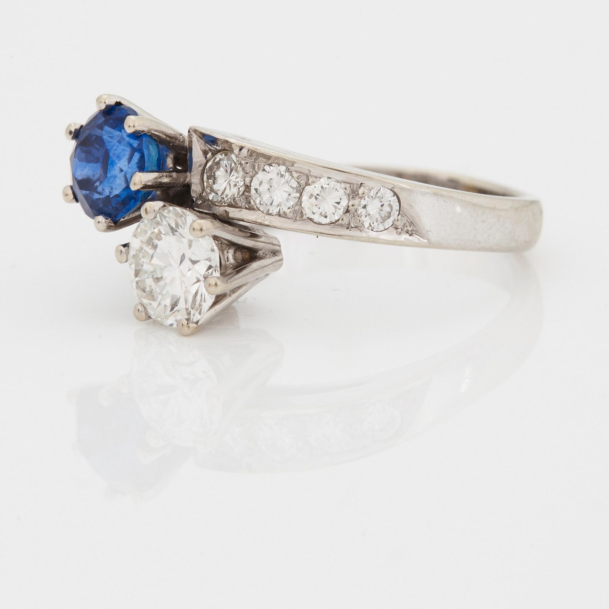 A CROSS-OVER RING set with a round mixed-cut sapphire and round brilliant-cut diamonds.