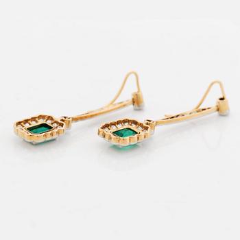 A pair of platinum and gold earrings set with step-cut emeralds and old-cut diamonds.