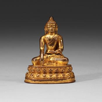 A gilt Tibetan bronze figure of Buddha, 16th Century or older.