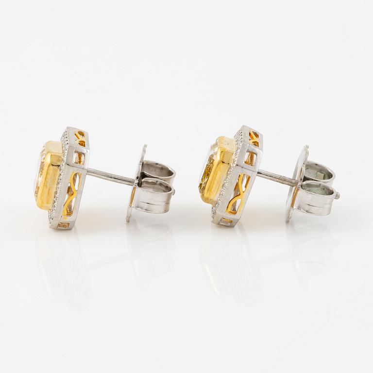 A pair of platinum and gold earrings with two radiant-cut yellow diamonds.
