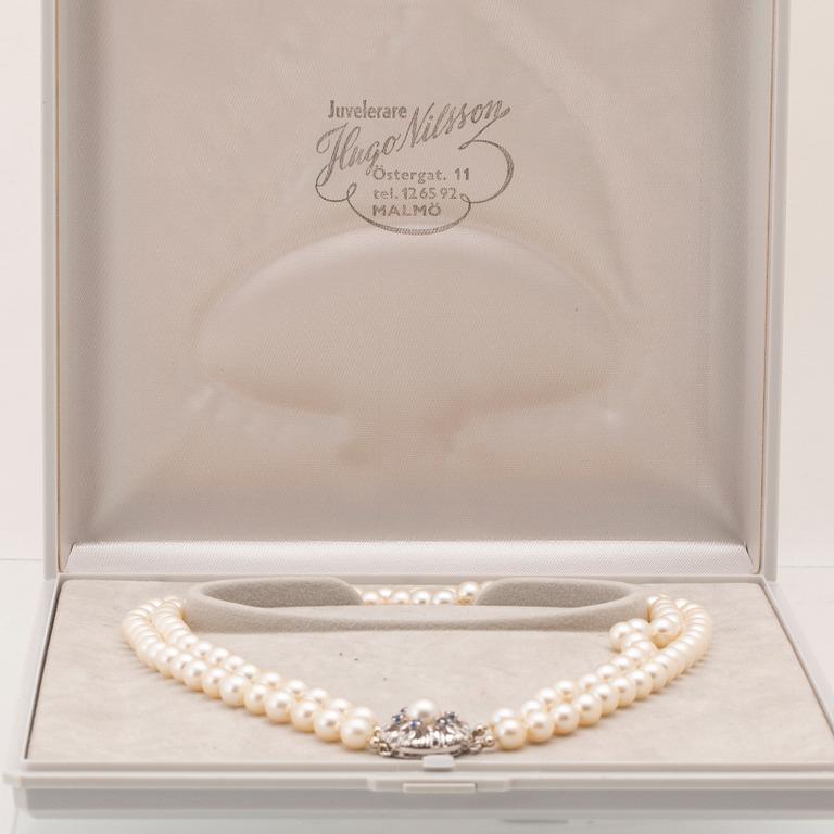 A double-stranded necklace of cultured pearls and an 18K white gold clasp with blue stones.