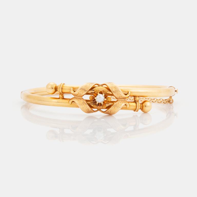 An 18K gold bangle set with a pearl.