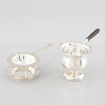 Two sterling silver tea strainers with stands, 20th century.