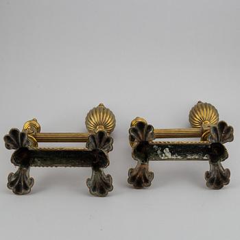 A pair of brass fire dogs and a brass fireplace poker set.