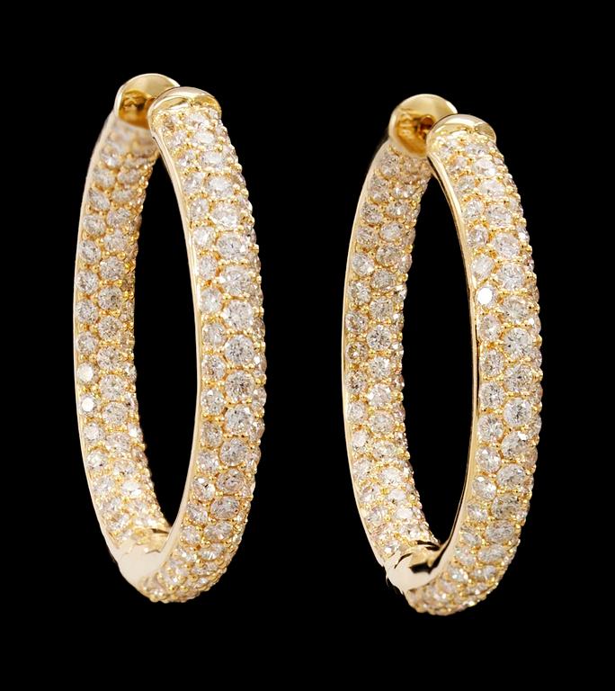 a pair of gold and diamond earrings.