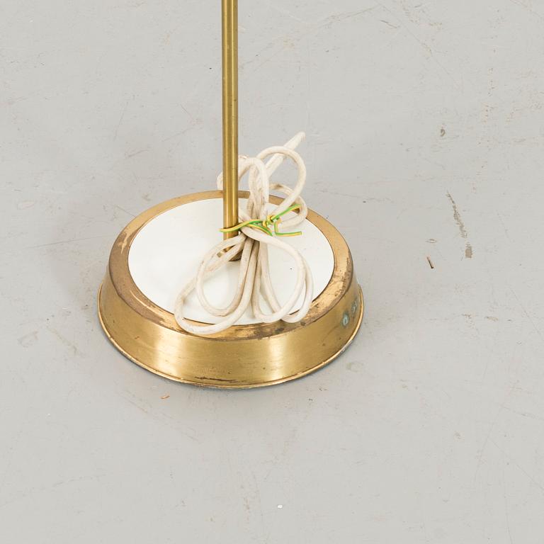 A brass floor light with white fabric lamp-shade.