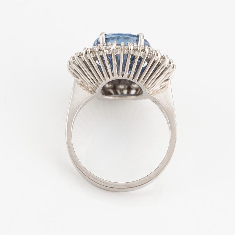 An 18K white gold Engelbert ring set with a sapphire and round brilliant-cut diamonds.