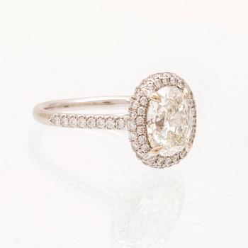 An 18K white gold ring by James Allen, set with an oval brilliant cut diamond in a halo of round brilliant cut diamonds.