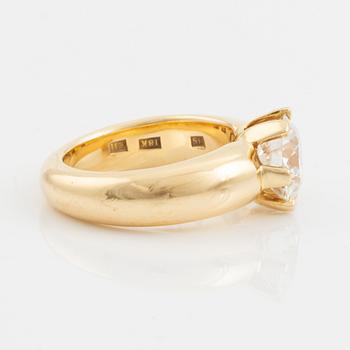 An 18K gold ring set with a round brilliant-cut diamond.