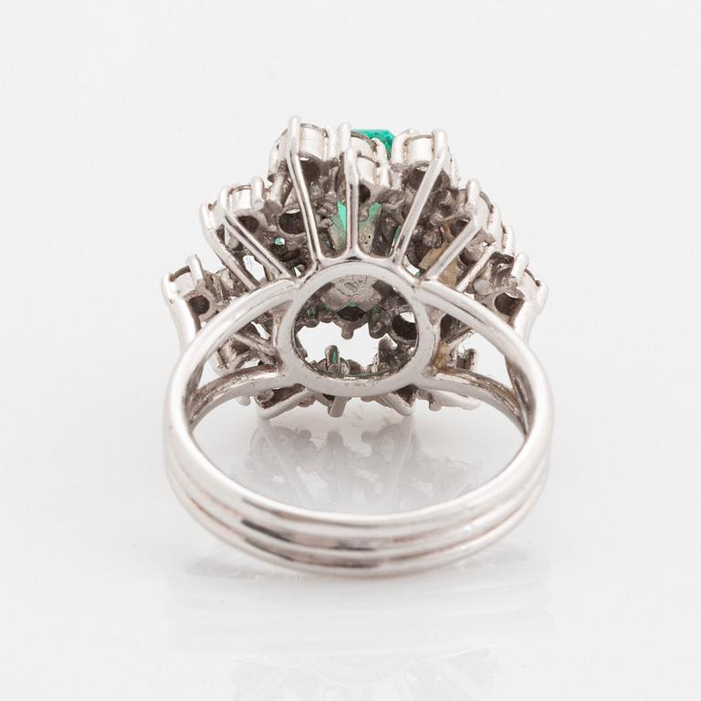 Ring platina med en fasettslipad smaragd och runda briljantslipade diamanter.