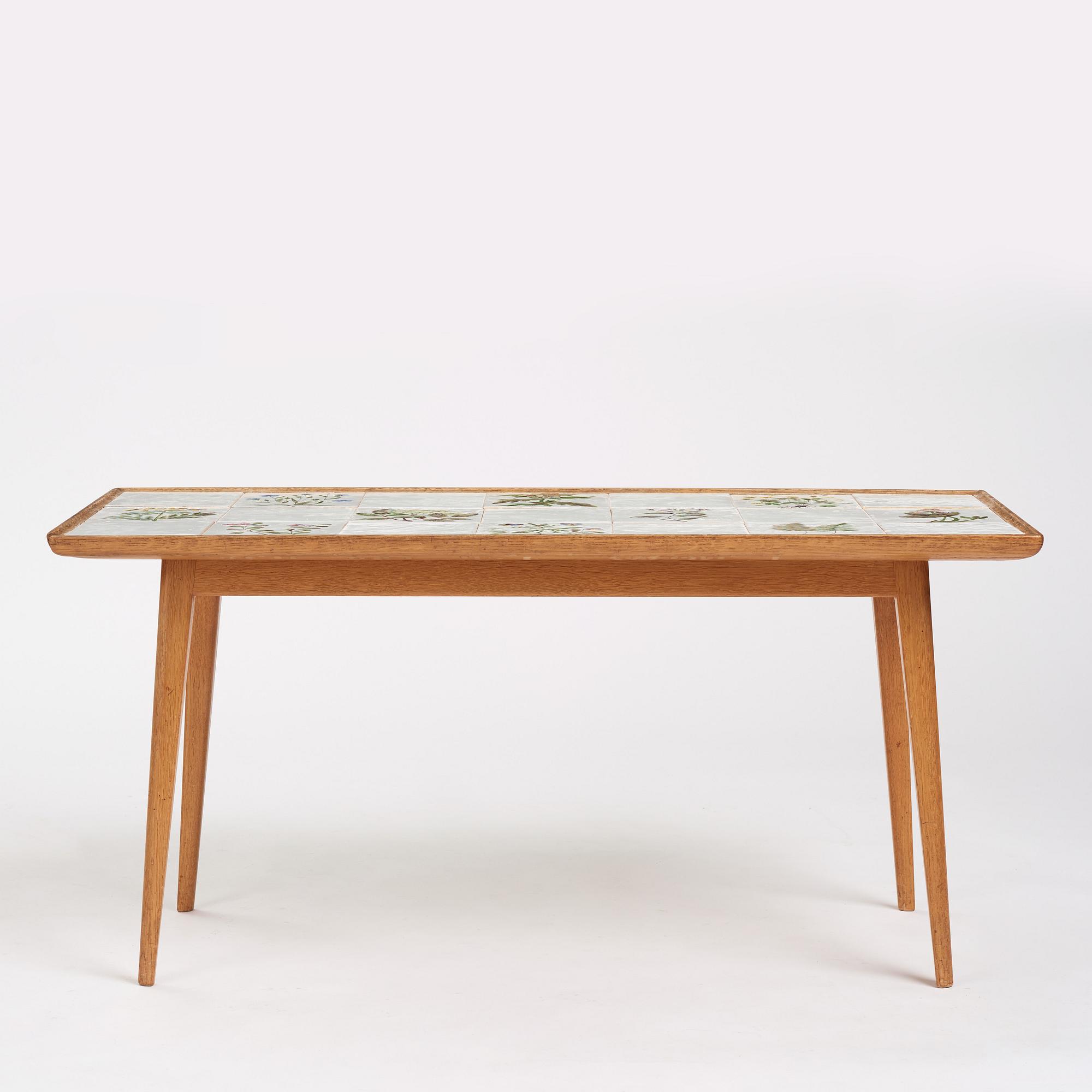 a Swedish Modern coffee table, decorated with Jobs' ceramic tiles, signed and dated 1941.