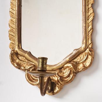 A pair of presumably German rococo giltwood one-branch mirrored wall-sconces, mid 18th century.