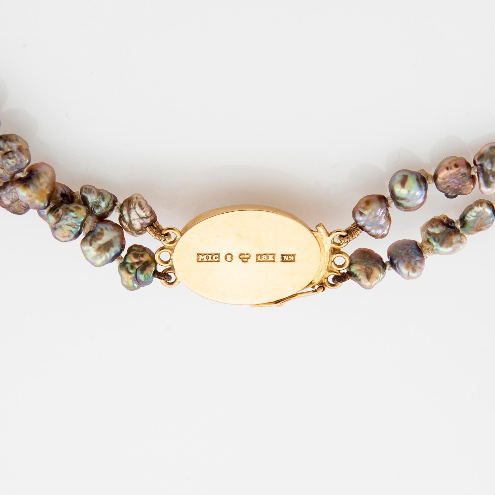 Necklace of cultured pearls with a clasp of 18K gold and cabochon-cut likely tourmaline.