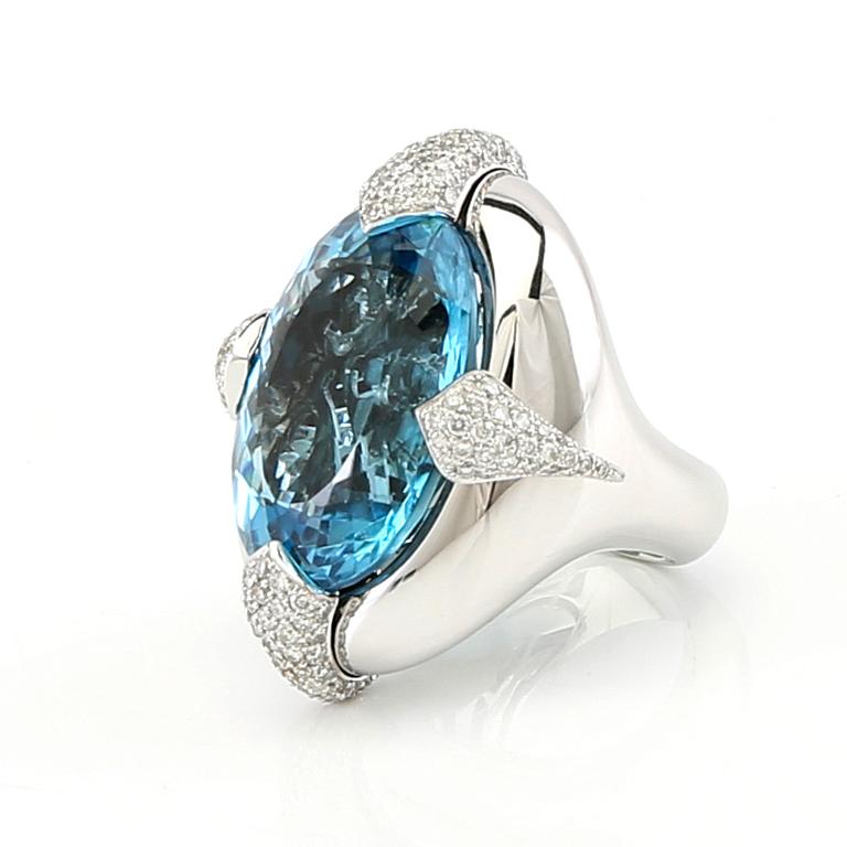 Pavé-set ring/cocktail ring in 18K white gold with an oval faceted blue topaz and round brilliant-cut diamonds.