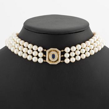 Pearl necklace, three strands of cultured pearls, with a clasp in 18K gold set with a sapphire and brilliant-cut diamonds.