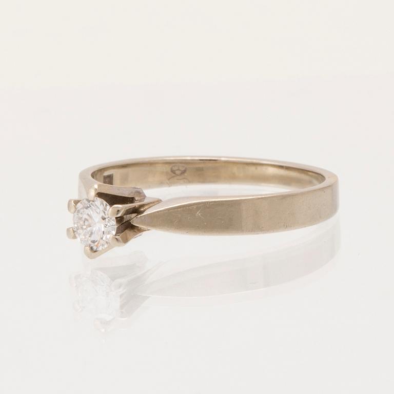 An 18K white gold solitaire ring set with a round brilliant-cut diamond.