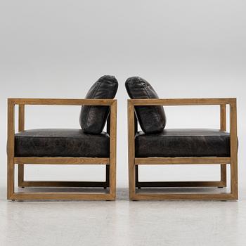 A pair of oak easy chairs with leather upholstered cushions from Artwood.