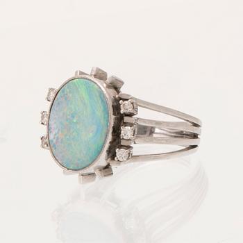 A 14K white gold ring set with an opal doublet or triplet and round brilliant-cut diamonds.