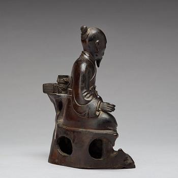 A bronze sculpture of a seated scholar with books, Qing dynasty (1644-1912).