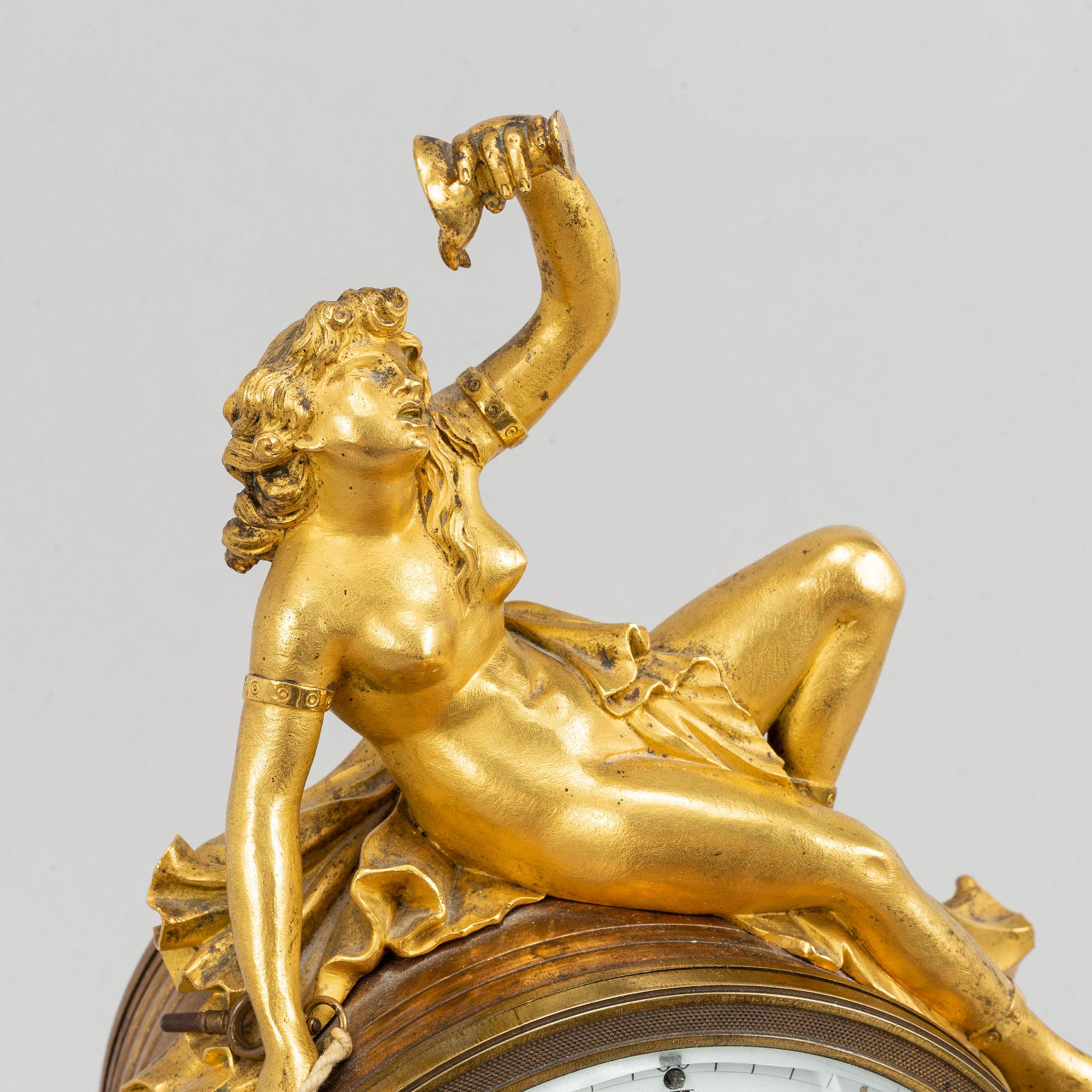 A marble and gilt bronze mantle clock in Louis XVI style, decorated with grapes, putti and a bacchant, 19th century.