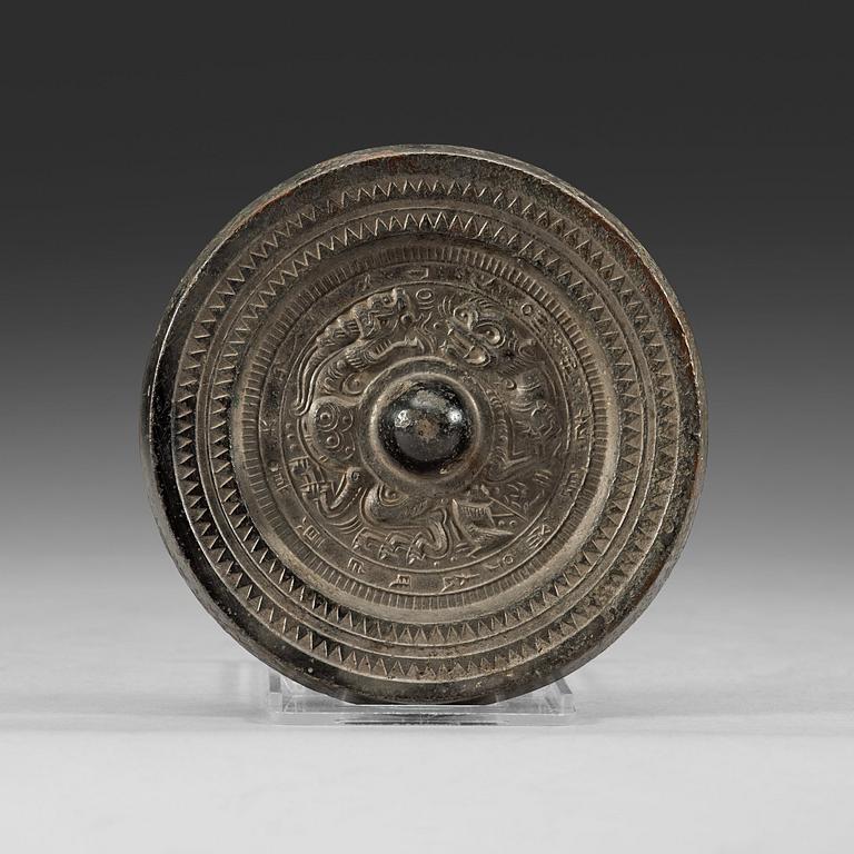 A bronze mirror decorated with characters a stylized dragon and tiger, Eastern Han dynasty (25-220).