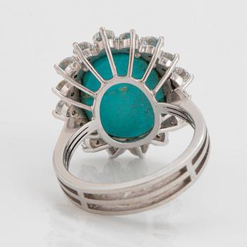 An 18K white gold ring set with a cabochon-cut turquoise and round brilliant-cut diamonds.