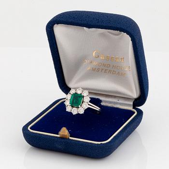 An 18K white gold ring set with a faceted emerald ca 1.15 cts and round brilliant-cut diamonds.