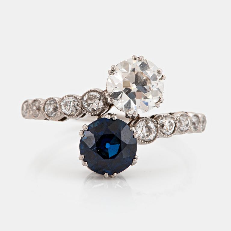 A platinum ring set with old-cut diamonds and a faceted sapphire.