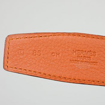 HERMÈS, a reversible belt, togo orange and black leather with silver colored H belt buckle.