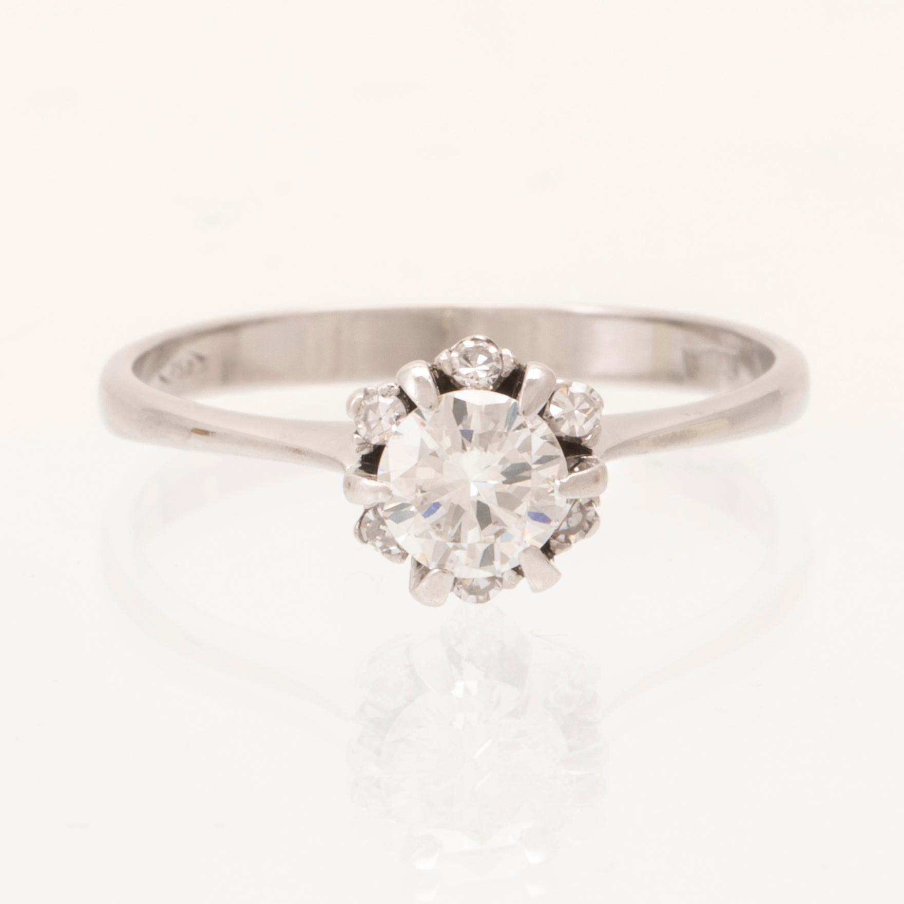 An 18K white gold ring set with a round brilliant cut diamond and single cut diamonds.