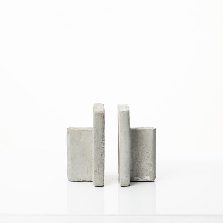 A mixed lot comprising a pair of limestone bookends, a bookshelf and two plates in concrete.