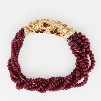 A Cartier chimera head bracelet in 18K gold set with round brilliant-cut diamonds and faceted rubies.