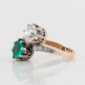 A CROSS-OVER RING set with an old-cut diamond and a round mixed-cut emerald.