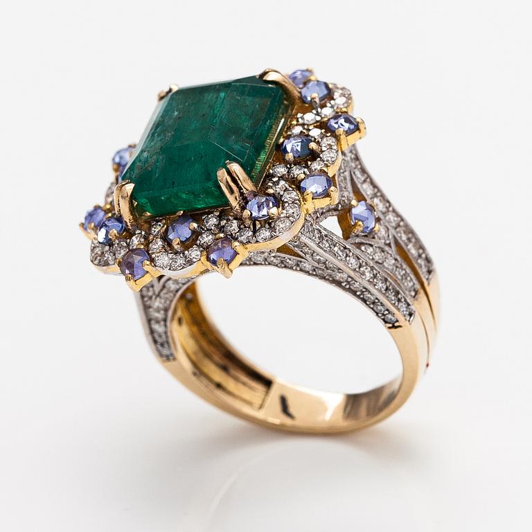 A 14k gold ring with an emerald ca. 6.39 ct, tanzanites and diamonds ca. 1.25 ct in total.