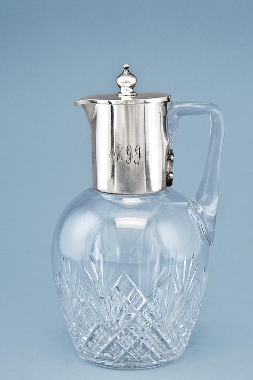 A CRYSTAL CARAFE WITH SILVER FITTINGS.