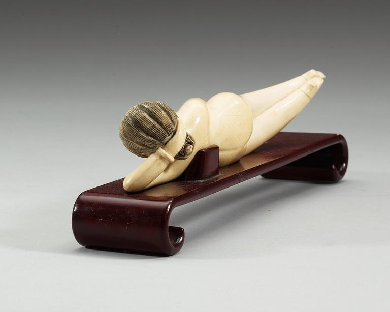 A ivory figure of a reclining 'Doctors Lady' on a wooden stand, Qing dynasty, circa 1900.