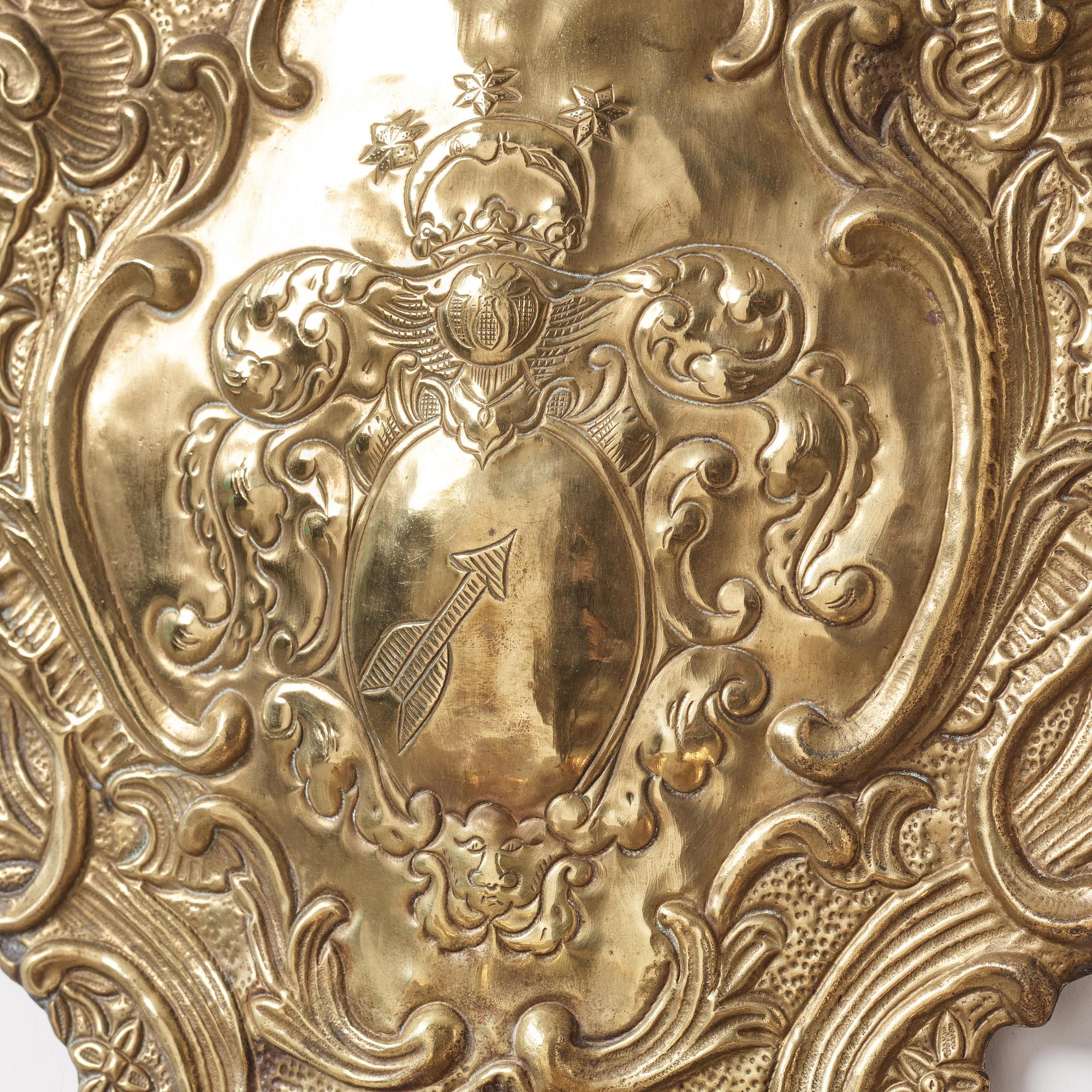 A pair of North European Rococo two-branch repoussé brass reflector plates, mid 18th century.