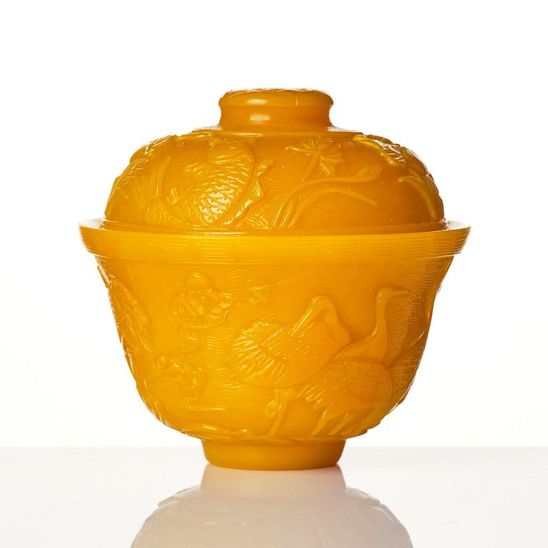 A well carved yellow glass 'crane and lotus' cup with cover, presumably late Qing dynasty.