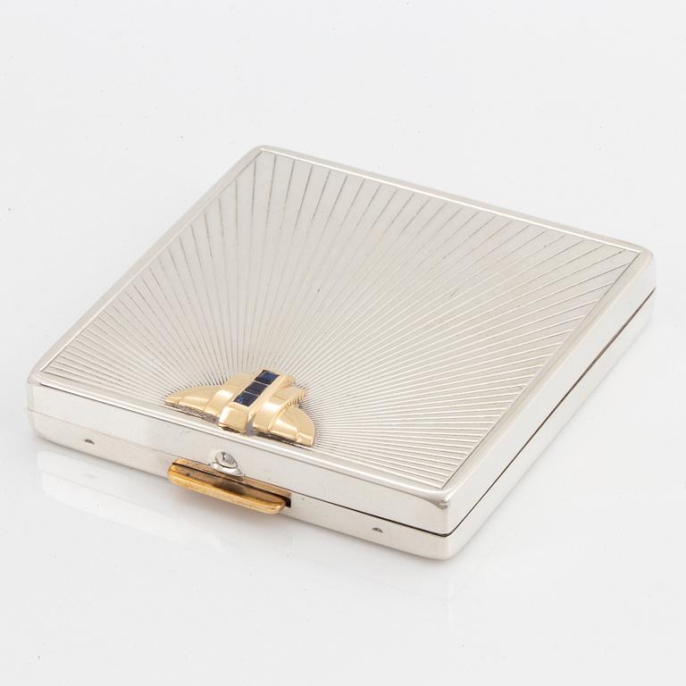 A powder case in silver and 14K gold set with faceted sapphires.