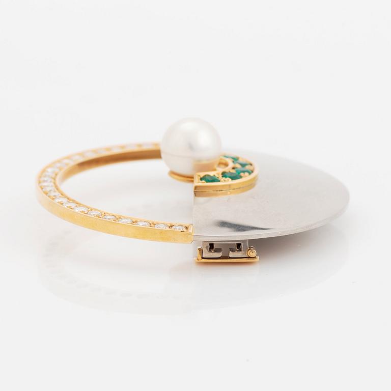 An 18K gold and white gold brooch set with a cultured pearl, round brilliant-cut diamonds and emeralds.