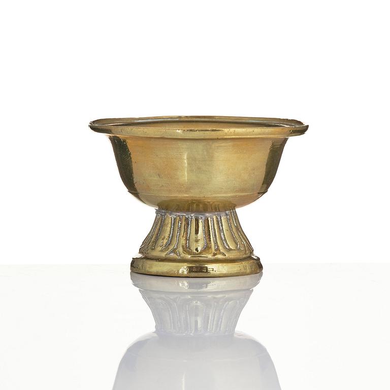 A bronze deity and a brass sacrificial bowl, Tibet, circa 1900.