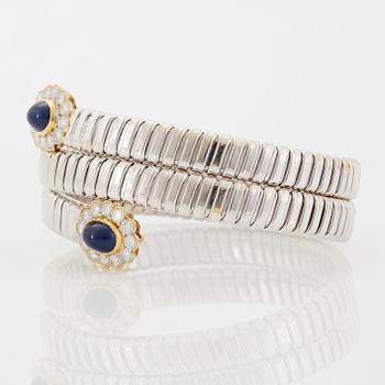 An 18K gold bangle set with cabochon-cut sapphires and round brilliant-cut diamonds.