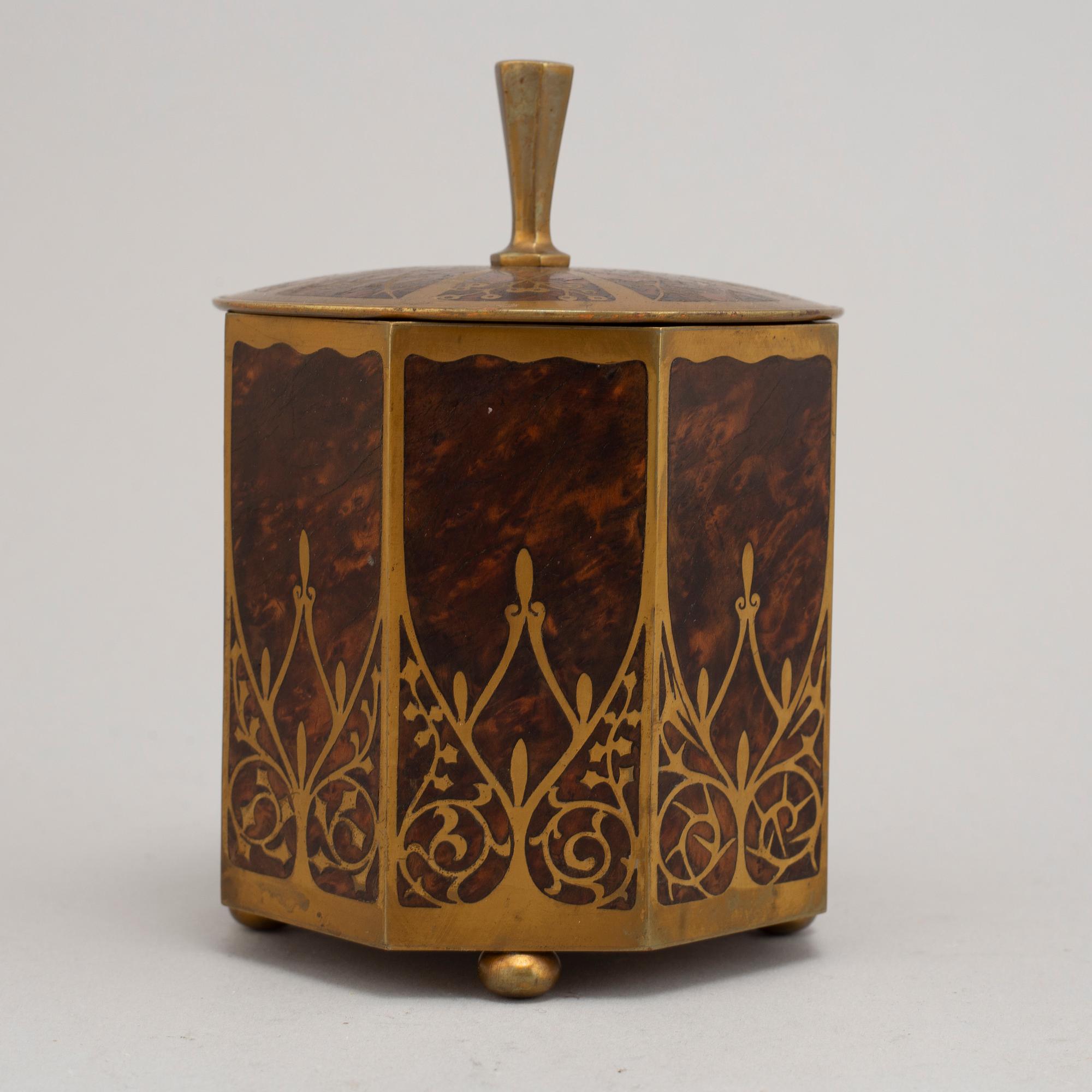 An art nouveau brass and burr walnut tobacco jar and cover from around year 1900.
