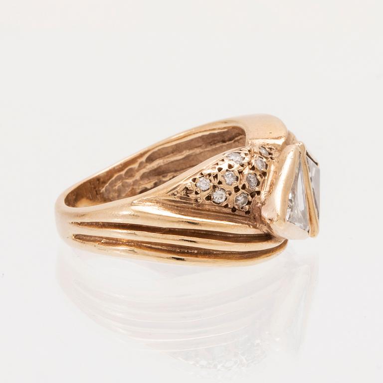 A 14K gold ring set with trillion and round brilliant cut diamonds.